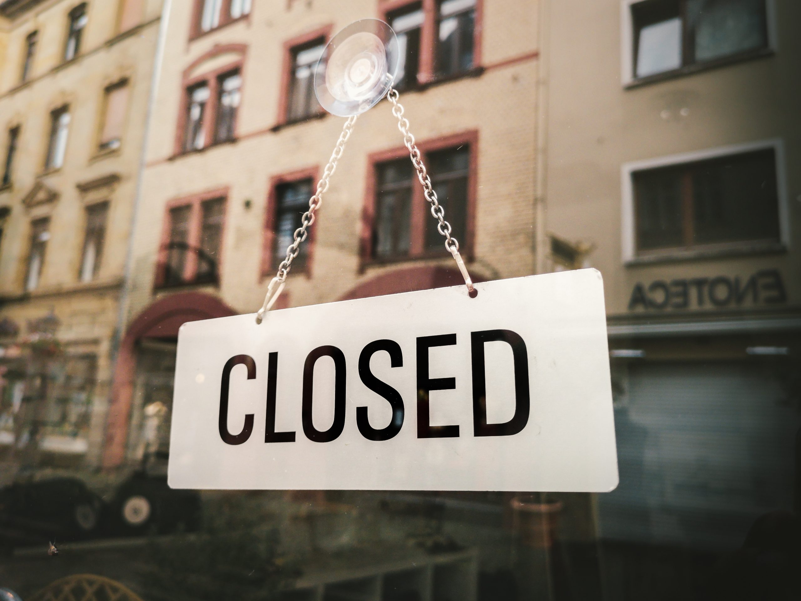 white closed sign hanging on glass